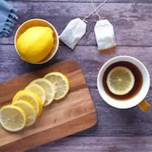 tea with lemon next to additional tea bags and lemon slices